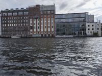 large body of water next to a building near the river with people on it and boats in the water