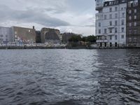 large body of water next to a building near the river with people on it and boats in the water