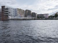 large body of water next to a building near the river with people on it and boats in the water