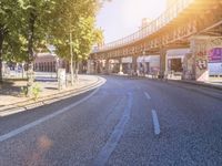 an empty city street with a bridge in the distance and buildings on either side of it