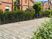 a brick path leads up to the brick facade of an old building with a fence surrounding