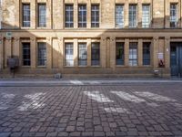 a brick street next to buildings and a fire hydrant in front of it with sun glaring in through the windows