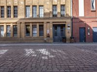 a brick street next to buildings and a fire hydrant in front of it with sun glaring in through the windows