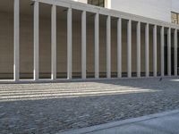 there is a bench near the columns of an outdoor building with no door or windows