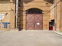 there is an outside area with a building and two brick walls and a red door