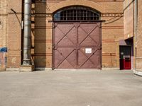 there is an outside area with a building and two brick walls and a red door