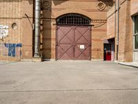 there is an outside area with a building and two brick walls and a red door