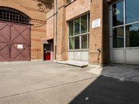 there is an outside area with a building and two brick walls and a red door