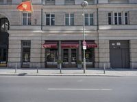 the building has a vietnamese flag hanging from the sidewalk outside of it to protect from the sun