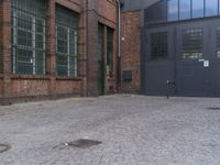 a yellow fire hydrant in front of a brick building with many windows and a door