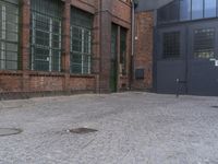 a yellow fire hydrant in front of a brick building with many windows and a door