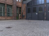 a yellow fire hydrant in front of a brick building with many windows and a door