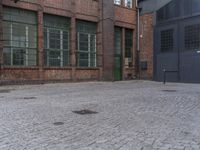 a yellow fire hydrant in front of a brick building with many windows and a door