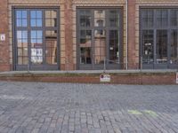 a brick building with a fire hydrant outside of it on a brick sidewalk next to a building that has several large windows