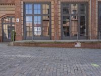 a brick building with a fire hydrant outside of it on a brick sidewalk next to a building that has several large windows