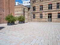 a brick courtyard area with some planters and a lamp post on the corner and on the ground