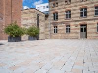 a brick courtyard area with some planters and a lamp post on the corner and on the ground