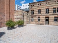 a brick courtyard area with some planters and a lamp post on the corner and on the ground