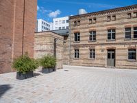 a brick courtyard area with some planters and a lamp post on the corner and on the ground