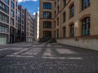 a brick courtyard has steps leading up to it, and a blue umbrella is on the ground