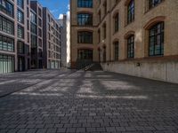 a brick courtyard has steps leading up to it, and a blue umbrella is on the ground