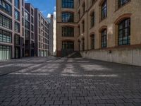 a brick courtyard has steps leading up to it, and a blue umbrella is on the ground