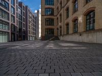 a brick courtyard has steps leading up to it, and a blue umbrella is on the ground