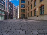 a brick courtyard has steps leading up to it, and a blue umbrella is on the ground