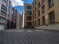 a brick courtyard has steps leading up to it, and a blue umbrella is on the ground