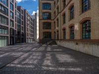 a brick courtyard has steps leading up to it, and a blue umbrella is on the ground