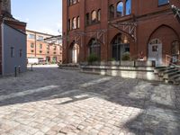 brick walkway next to buildings with stairs leading up to the outside of them while buildings are seen in the background