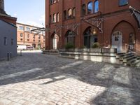 brick walkway next to buildings with stairs leading up to the outside of them while buildings are seen in the background