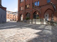 brick walkway next to buildings with stairs leading up to the outside of them while buildings are seen in the background