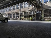 a military vehicle parked inside of a building near a street with brick flooring and potted planters in front of it