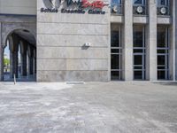 the front entrance to a building with concrete floors and stone work on it, leading up to a tall white wall