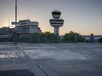 some cars are parked at an air traffic control tower with smoke coming from the air