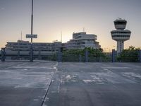 some cars are parked at an air traffic control tower with smoke coming from the air