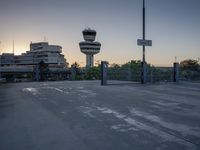some cars are parked at an air traffic control tower with smoke coming from the air