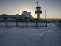 some cars are parked at an air traffic control tower with smoke coming from the air