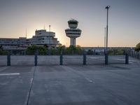 some cars are parked at an air traffic control tower with smoke coming from the air