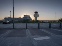 some cars are parked at an air traffic control tower with smoke coming from the air