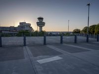 some cars are parked at an air traffic control tower with smoke coming from the air