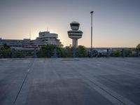 some cars are parked at an air traffic control tower with smoke coming from the air