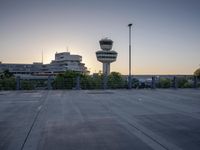 some cars are parked at an air traffic control tower with smoke coming from the air