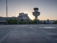 some cars are parked at an air traffic control tower with smoke coming from the air