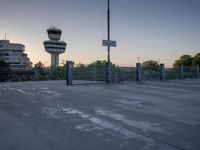some cars are parked at an air traffic control tower with smoke coming from the air