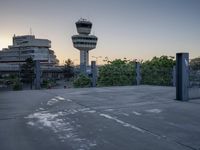 some cars are parked at an air traffic control tower with smoke coming from the air