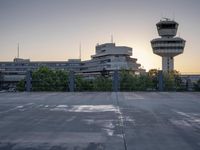 some cars are parked at an air traffic control tower with smoke coming from the air