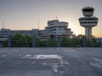 some cars are parked at an air traffic control tower with smoke coming from the air