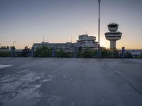 some cars are parked at an air traffic control tower with smoke coming from the air